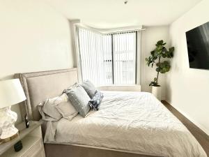 ein weißes Schlafzimmer mit einem Bett mit Kissen und einem Fenster in der Unterkunft Spacious and Central with a Pool View in Los Angeles