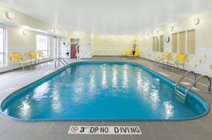 a pool in a hotel room with chairs and tables at Fairfield Inn & Suites Findlay in Findlay
