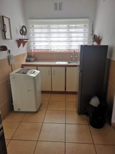 a kitchen with a refrigerator and a sink and a window at Michelle's Cottage by the Sea in Port Shepstone