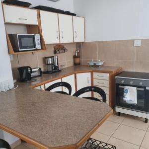 a kitchen with white cabinets and a table with chairs at Michelle's Cottage by the Sea in Port Shepstone +32 photos