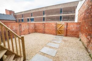 a brick walled courtyard with a staircase and a building at The Cheltenham Suites - Elegant 1 Bed Apartment in Cheltenham