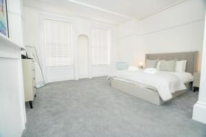 a white bedroom with a large bed and a dresser at The Cheltenham Suites - Elegant 1 Bed Apartment in Cheltenham