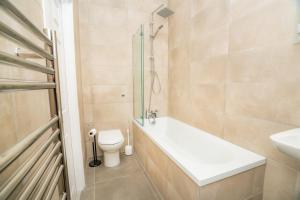 a bathroom with a tub and a toilet and a sink at The Cheltenham Suites - Elegant 1 Bed Apartment in Cheltenham