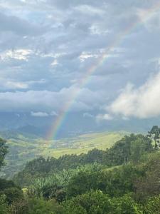 a rainbow in the sky over a field with trees at Sitio São Sebastião in São Bento do Sapucaí