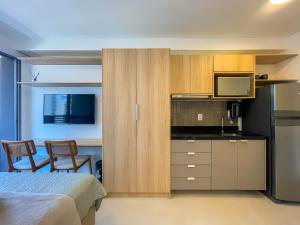 Nine: Conforto e Sofisticação no Jardim Paulista في ساو باولو: غرفة نوم مع سرير ومطبخ مع دواليب