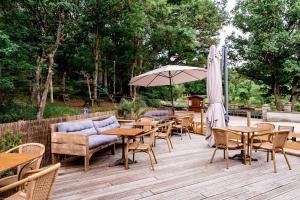a patio with tables and chairs and an umbrella at La Maison du Gasseau in Saint-Léonard-des-Bois