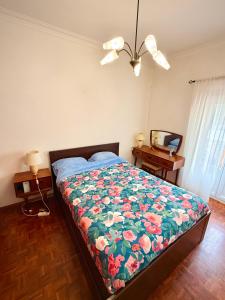 a bedroom with a bed with a floral comforter at Casa da Mariazinha in Costa da Caparica