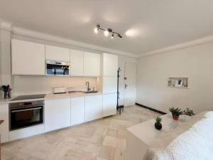 a kitchen with white cabinets and a bed in a room at Le balcon du Hautacam in Argelès-Gazost