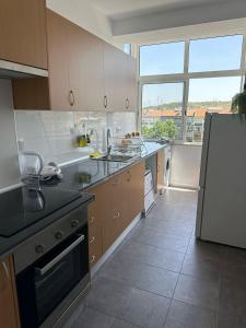 a kitchen with a refrigerator and a large window at Hostel Nosso Lar in Odivelas