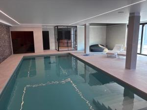 a large swimming pool in a room with a couch at Gite New-York - Domaine aux charmes d'Ethan - Piscine en option in Hannut