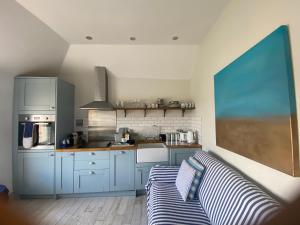 a kitchen with blue cabinets and a couch in a room at Little Dolly sea view 2 bedroom apartment, St Ives town, dog friendly in St Ives +16 photos