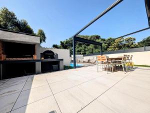 a patio with a table and chairs and a fireplace at Villa plein Sud, clim et piscine, 6 à 8 personnes in Boisseron
