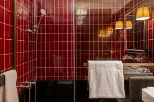 uma casa de banho em azulejos vermelhos com um lavatório e toalhas em Hotel Kindli em Zurique