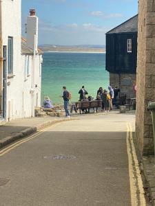 a group of people walking on a sidewalk near the ocean at Little Dolly sea view 2 bedroom apartment, St Ives town, dog friendly in St Ives