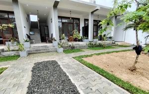 a house with a courtyard with a palm tree at Surfing Pinthaliya - Midigama in Weligama
