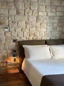 sypialnia z białym łóżkiem i ceglaną ścianą w obiekcie Olivia Rooms Eurialo w mieście Belvedere