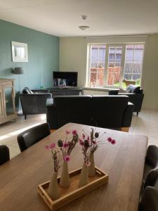 a dining room with a table with flowers in vases on it at Accommodatie in herbouwde boerenschuur Koestal in Retranchement