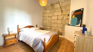a bedroom with a bed and a stone wall at Charmant T2 avec Jardin, Barrière St-Genes in Talence