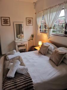 a bedroom with a large white bed with pillows at Michelle's Cottage by the Sea in Port Shepstone