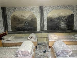 four beds in a room with paintings on the wall at Ikhtiyor guest house with mountainiring hiking horse riding serivices in Yukary-Ukhum