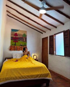 a woman sitting on a bed in a bedroom at Habitación Vanessa, una ó dos personas in Barichara