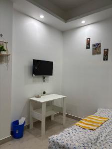 a white room with a table and a tv on a wall at Jassy haven in Guwahati