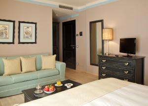 サン・カシャーノ・デイ・バーニにあるAlbergo La Fontanellaのベッド、ソファ、テレビが備わるホテルルームです。