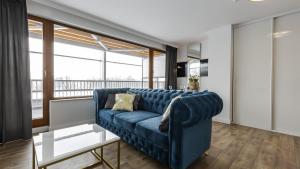 a blue couch in a living room with a large window at LABA Kołobrzeg Royal Tulip Sand apartament prywatny, Basen w CENIE, Schwimmbad im PREIS in Kołobrzeg