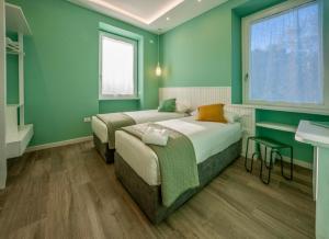 a green bedroom with two beds and a sink at DomusBiri in Bracciano
