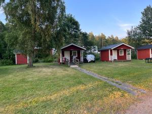 a group of huts in a yard with a tree at Klämmingsbergsbadets - STUGA ABBORREN in Gnesta