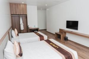 um quarto de hotel com duas camas e uma TV de tela plana em Long Hải Hotel em Móng Cái