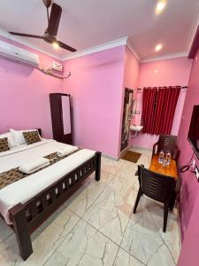 una camera da letto con pareti rosa, un letto e un tavolo di Le Oasis Auro'Ra a Pondicherry Altre 65 foto