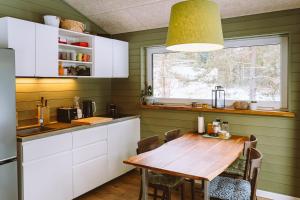 eine Küche mit einem Holztisch und einem Fenster in der Unterkunft Luxury cabins with own sauna and hot-tub in Ķesterciems