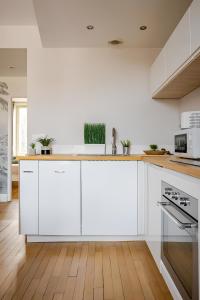 a white kitchen with white cabinets and a wooden floor at Nancy Ville in Nancy