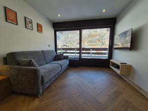 ein Wohnzimmer mit Couch und großem Fenster in der Unterkunft ROCH B300 - Magnifique studio - Centre Bourg Saint Maurice in Bourg-Saint-Maurice