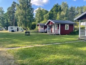 a campsite with a trailer and a picnic table in the grass at Klämmingsbergsbadets - STUGA GÄDDAN in Gnesta