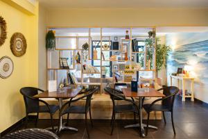 a restaurant with two tables and chairs in a room at Hôtel les jardins du canal - piscine chauffée - solaire eco responsable - parking - garage - bornes électriques - accueil vélos - kids friendly in Aigues-Mortes