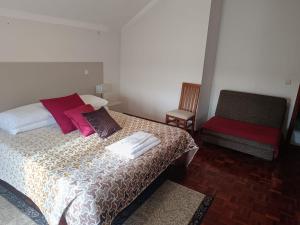 a bedroom with a bed with two pillows and a chair at Casa do Outeirinho in Campos +2 photos