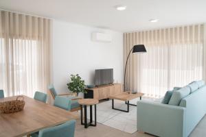 a living room with a table and chairs and a television at Casa Encanto da Foz - BY SCH in Foz do Arelho