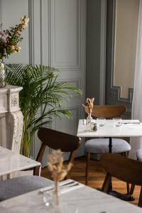 a dining room with two white tables and chairs at Le Charmant Hôtel in Saint-Ouen
