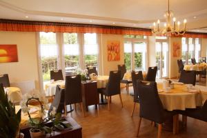 a dining room with tables and chairs and windows at Gästehaus Linde in Heringsdorf