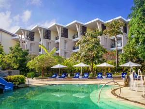 a hotel with a swimming pool with chairs and umbrellas at Sofitel Bali Nusa Dua Beach Resort in Nusa Dua