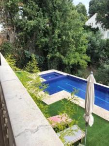 a swimming pool in a yard with an umbrella at Villa spacieuse avec piscine à Rayol-Canadel-sur-Mer in Rayol-Canadel-sur-Mer
