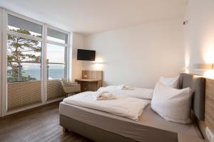 a bedroom with a bed and a large window at Hotel Seebrücke in Lubmin