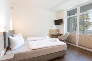 a bedroom with two beds and a tv and a window at Hotel Seebrücke in Lubmin