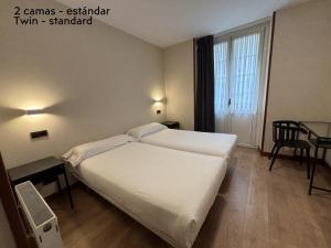 a hotel room with a large bed and a table at Pensión Begoña - centro ciudad in Bilbao