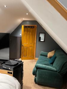 a living room with a green couch in a attic at Manor Gardens in Westbury