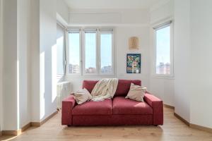 - un canapé rouge dans une pièce avec fenêtres dans l'établissement Urban View Apartment - Argonne, à Milan
