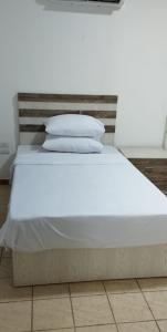 un letto con lenzuola bianche e cuscini sopra di Cali Residence a Sharm El Sheikh