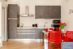 a kitchen with a table and red chairs in a room at Lele Home Bilocale nel centro città 900m dalla stazione in Lissone +10 photos
